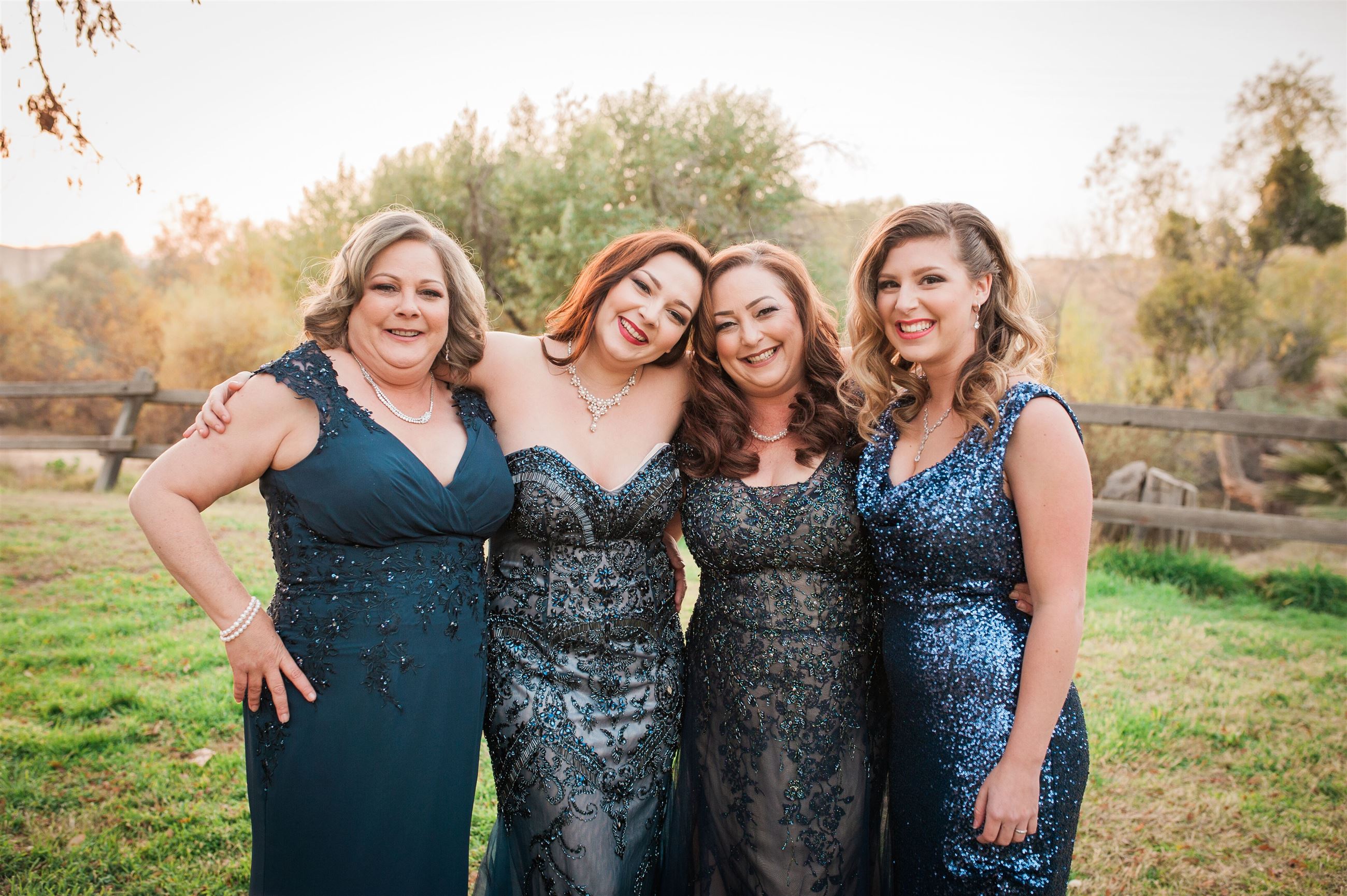 Four happy women wearing blue evening dresses in different styles
